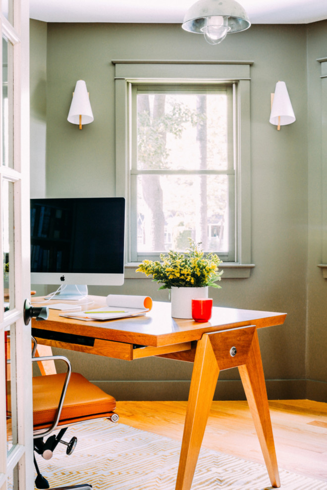 На фото: кабинет в стиле кантри с зелеными стенами, светлым паркетным полом и отдельно стоящим рабочим столом с