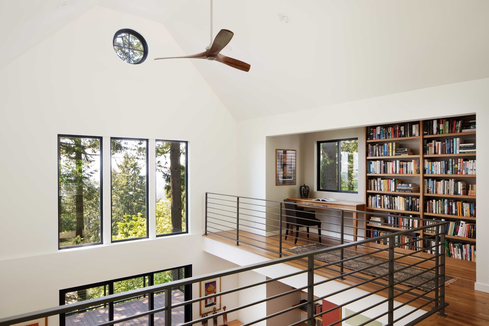 Diseño de despacho contemporáneo de tamaño medio sin chimenea con biblioteca, paredes blancas, suelo de madera en tonos medios y escritorio empotrado