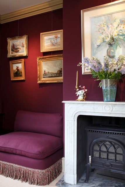 Cette photo montre un salon nature de taille moyenne avec un mur violet, moquette, un poêle à bois, un manteau de cheminée en pierre et un sol beige.