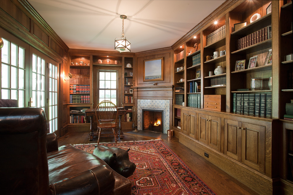 Idéer för ett stort klassiskt hemmabibliotek, med bruna väggar, mörkt trägolv, en öppen hörnspis, en spiselkrans i trä och ett fristående skrivbord