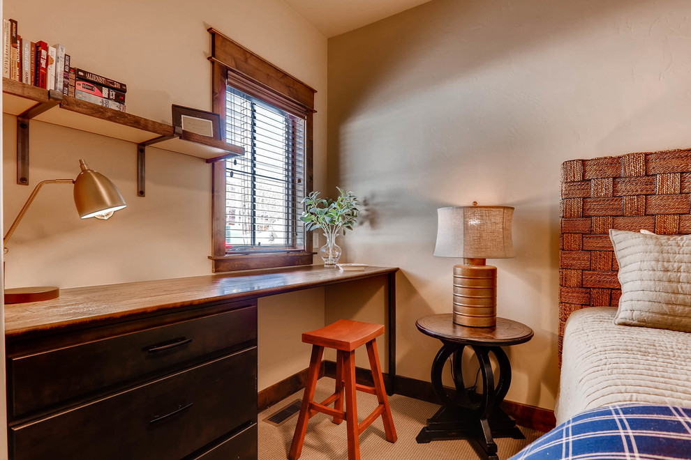 Bild på ett litet amerikanskt arbetsrum, med beige väggar, heltäckningsmatta, ett inbyggt skrivbord och beiget golv