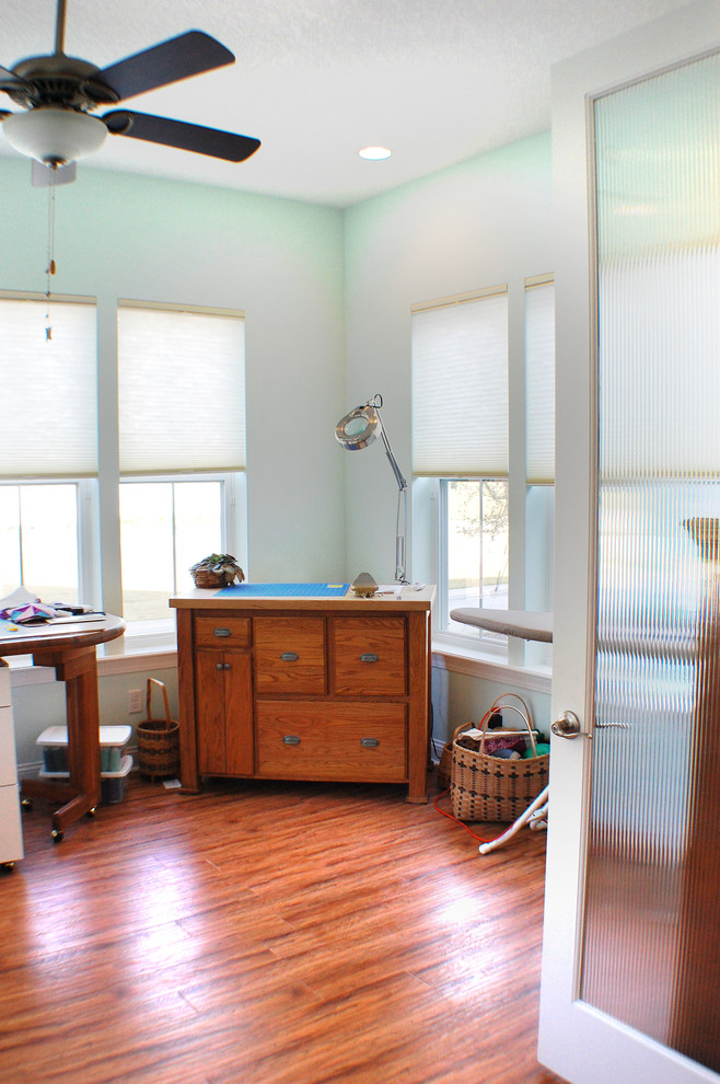 Mittelgroßes Country Nähzimmer mit blauer Wandfarbe, dunklem Holzboden und freistehendem Schreibtisch in Jacksonville