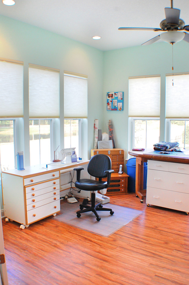 Mittelgroßes Landhaus Nähzimmer mit blauer Wandfarbe, dunklem Holzboden und freistehendem Schreibtisch in Jacksonville
