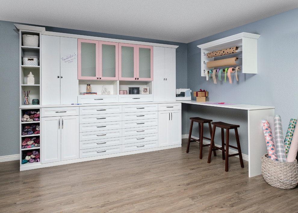 Ejemplo de sala de manualidades minimalista con paredes azules, suelo de madera en tonos medios, escritorio empotrado y suelo marrón