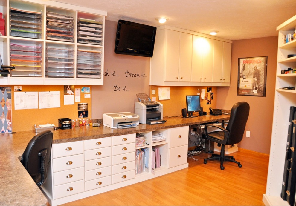 Imagen de sala de manualidades de tamaño medio con parades naranjas, suelo de madera en tonos medios y escritorio empotrado
