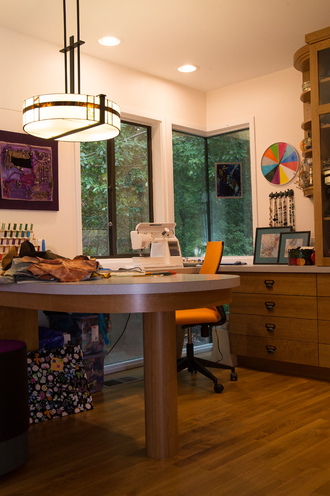 Aménagement d'un bureau atelier contemporain de taille moyenne avec un bureau intégré, un mur blanc, un sol en bois brun et un sol orange.