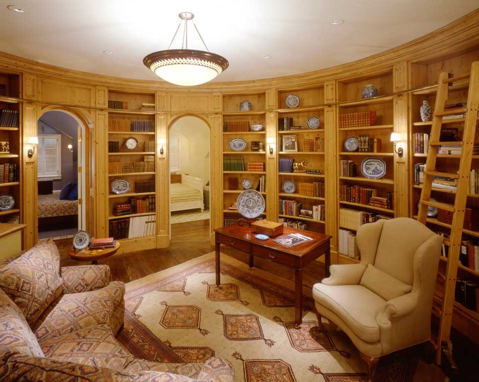 Inredning av ett klassiskt mellanstort hemmabibliotek, med bruna väggar, mellanmörkt trägolv och ett fristående skrivbord