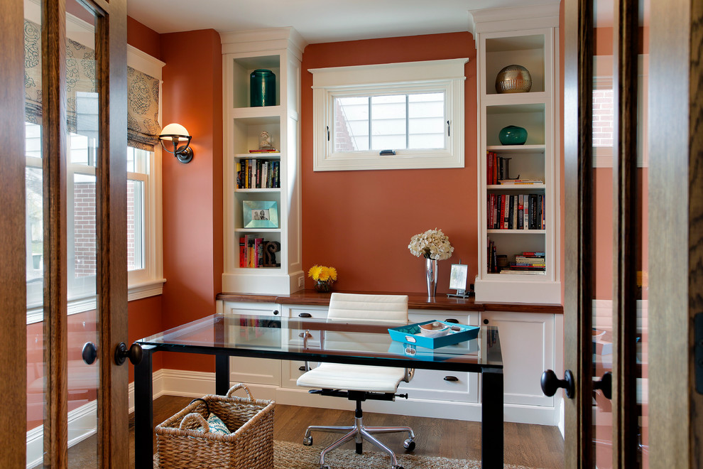 На фото: маленький кабинет в стиле кантри с оранжевыми стенами, темным паркетным полом и отдельно стоящим рабочим столом для на участке и в саду