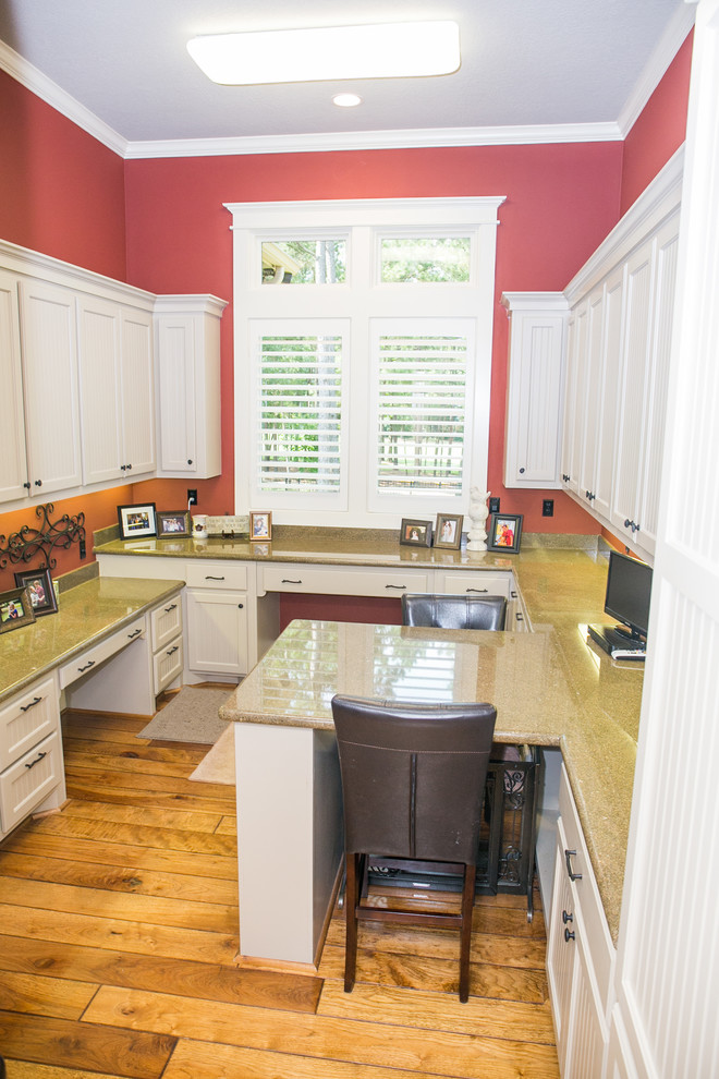 Example of a large arts and crafts built-in desk medium tone wood floor craft room design in Houston with red walls