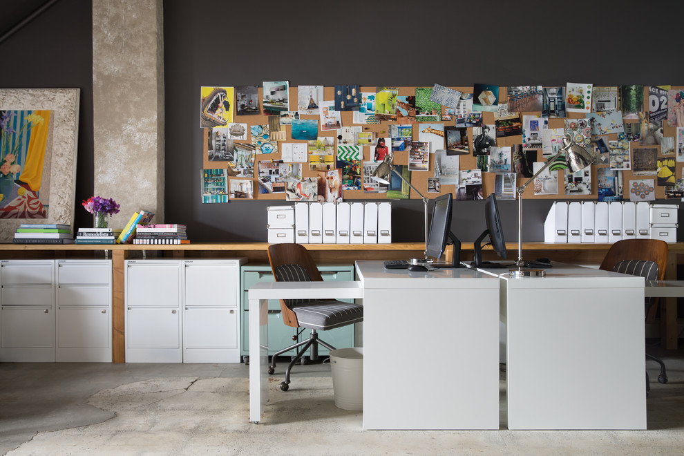 This is an example of a contemporary study in San Francisco with black walls, concrete flooring and a freestanding desk.