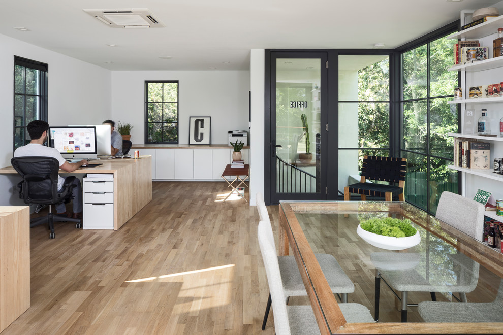 Kleines Modernes Arbeitszimmer ohne Kamin mit Studio, weißer Wandfarbe, hellem Holzboden, Kaminumrandung aus Backstein, Einbau-Schreibtisch und weißem Boden in Austin