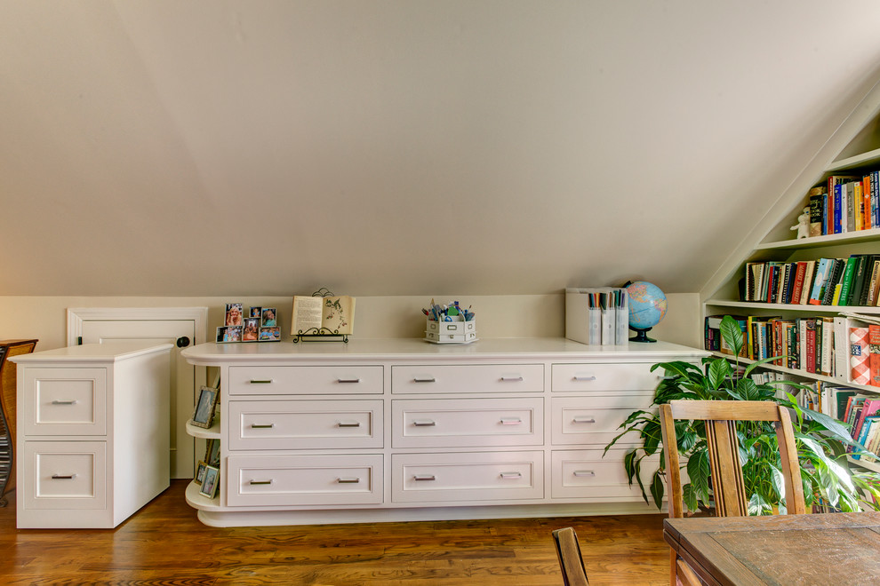 Diseño de despacho tradicional de tamaño medio sin chimenea con paredes beige, suelo de madera clara y escritorio independiente