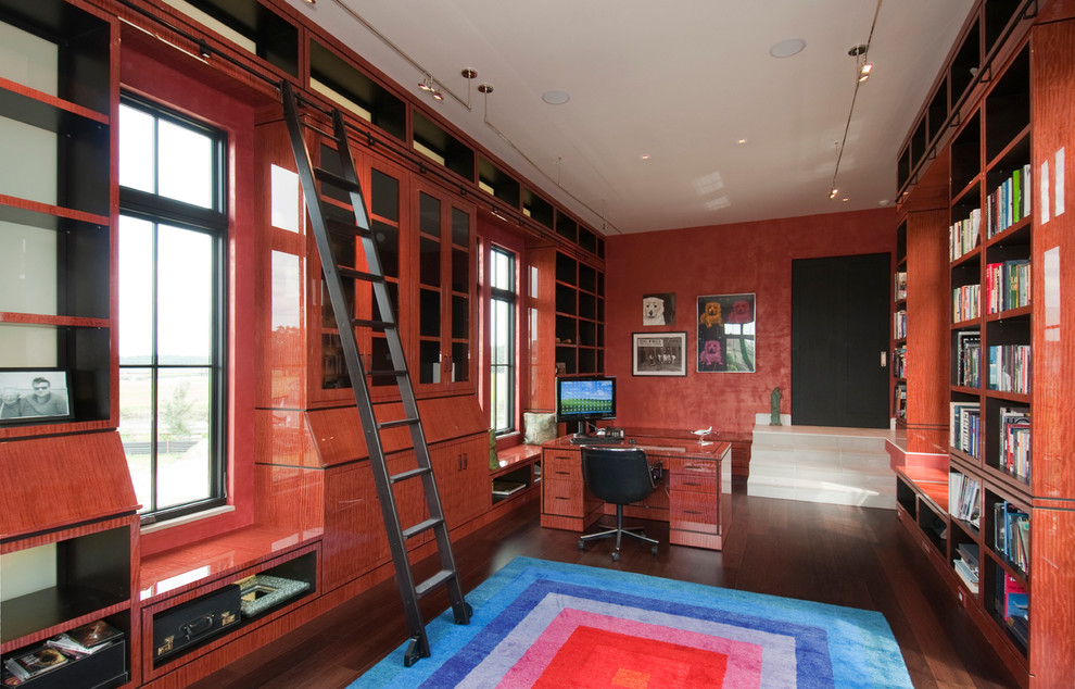 Foto på ett funkis arbetsrum, med mörkt trägolv, ett fristående skrivbord och röda väggar