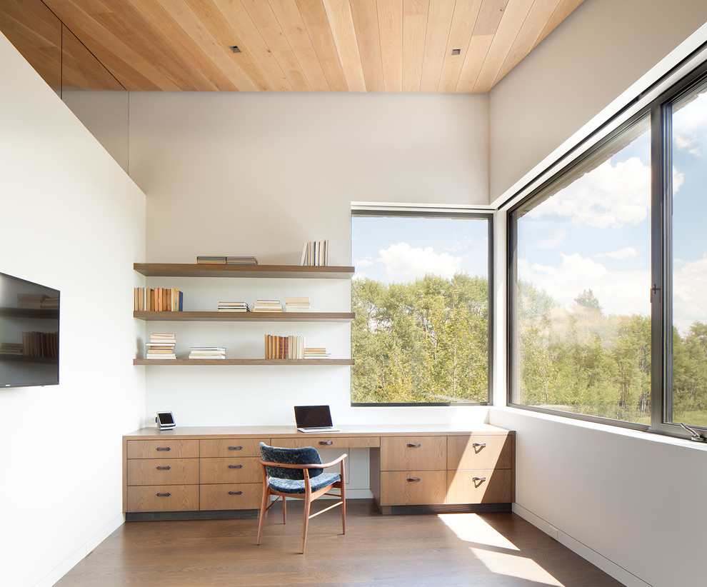 Modernes Arbeitszimmer mit Arbeitsplatz, weißer Wandfarbe, braunem Holzboden und Einbau-Schreibtisch in Sonstige
