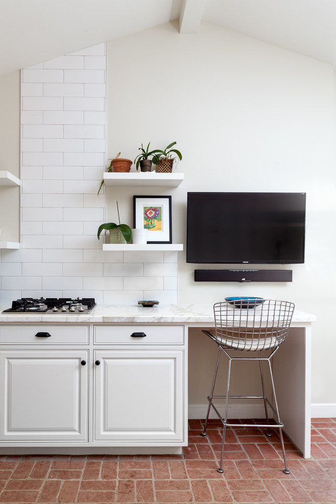 Cette image montre un bureau avec un mur beige, un sol en brique, aucune cheminée, un bureau intégré et un sol rouge.