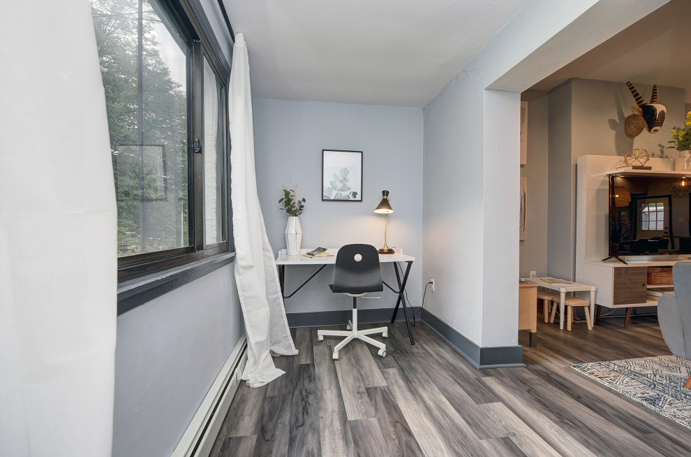 Kleines Modernes Arbeitszimmer ohne Kamin mit Arbeitsplatz, blauer Wandfarbe, freistehendem Schreibtisch und grauem Boden in Sonstige
