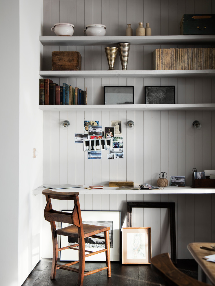 Diseño de despacho industrial pequeño con escritorio empotrado, paredes grises y suelo de madera oscura