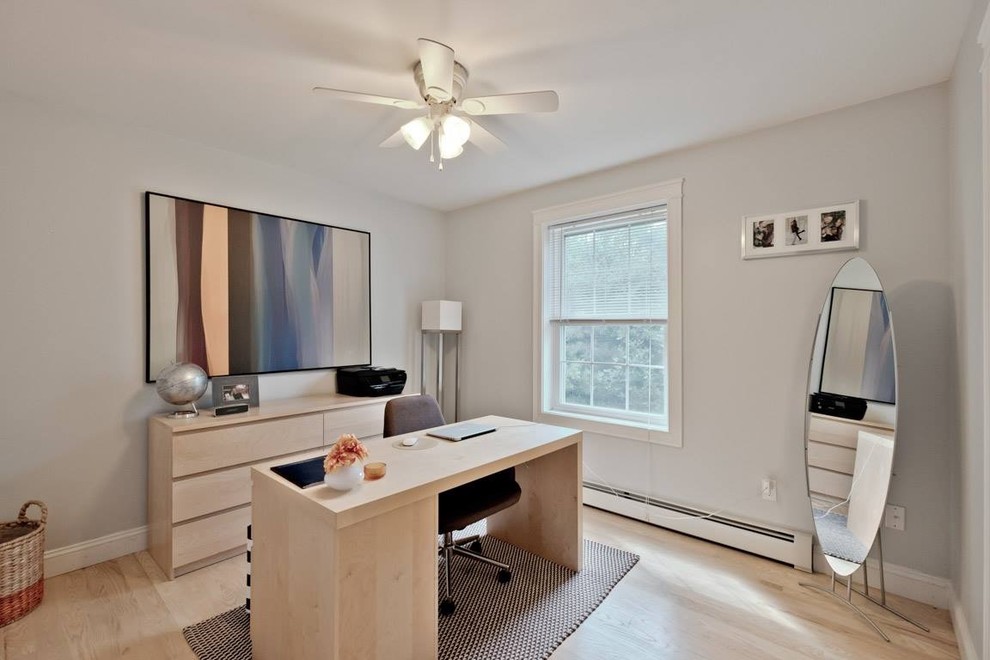 Imagen de despacho actual de tamaño medio sin chimenea con paredes grises, suelo de madera clara, escritorio independiente y suelo beige