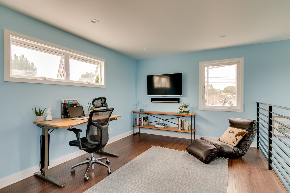Diseño de estudio contemporáneo de tamaño medio sin chimenea con paredes azules, suelo de madera en tonos medios, escritorio independiente y suelo marrón