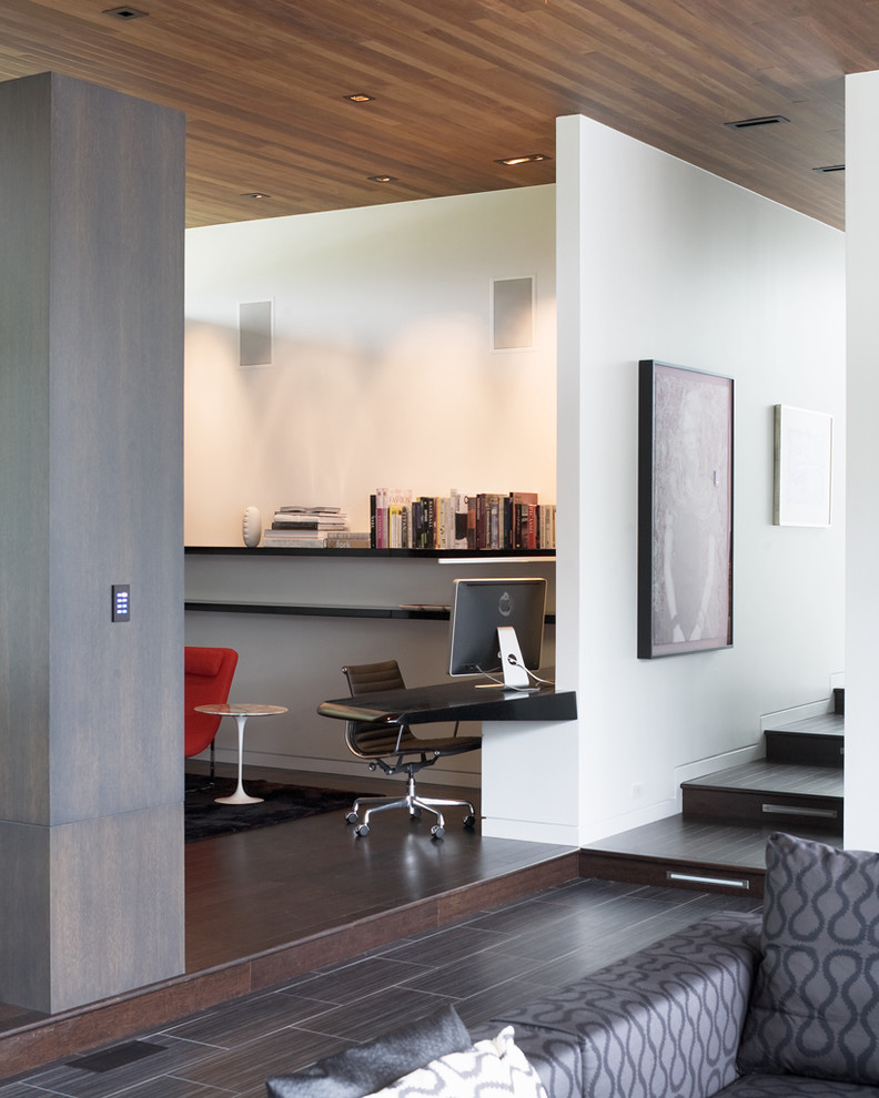 Стильный дизайн: кабинет в современном стиле с белыми стенами, темным паркетным полом, встроенным рабочим столом и коричневым полом - последний тренд