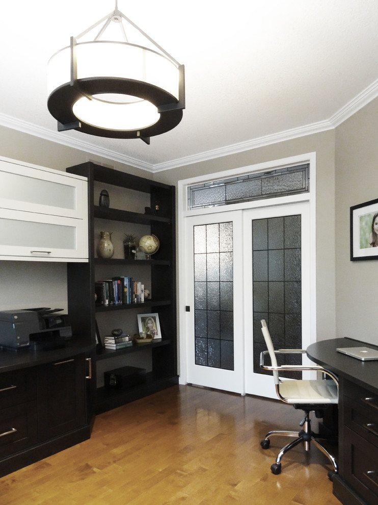 This is an example of a medium sized contemporary study in Toronto with beige walls, light hardwood flooring and a built-in desk.