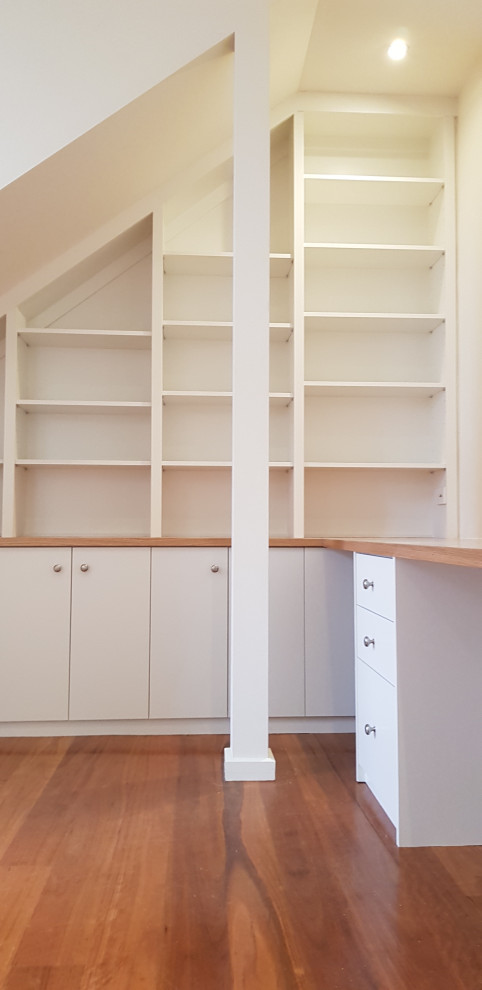 Idéer för att renovera ett litet vintage hemmabibliotek, med vita väggar, mellanmörkt trägolv och ett inbyggt skrivbord