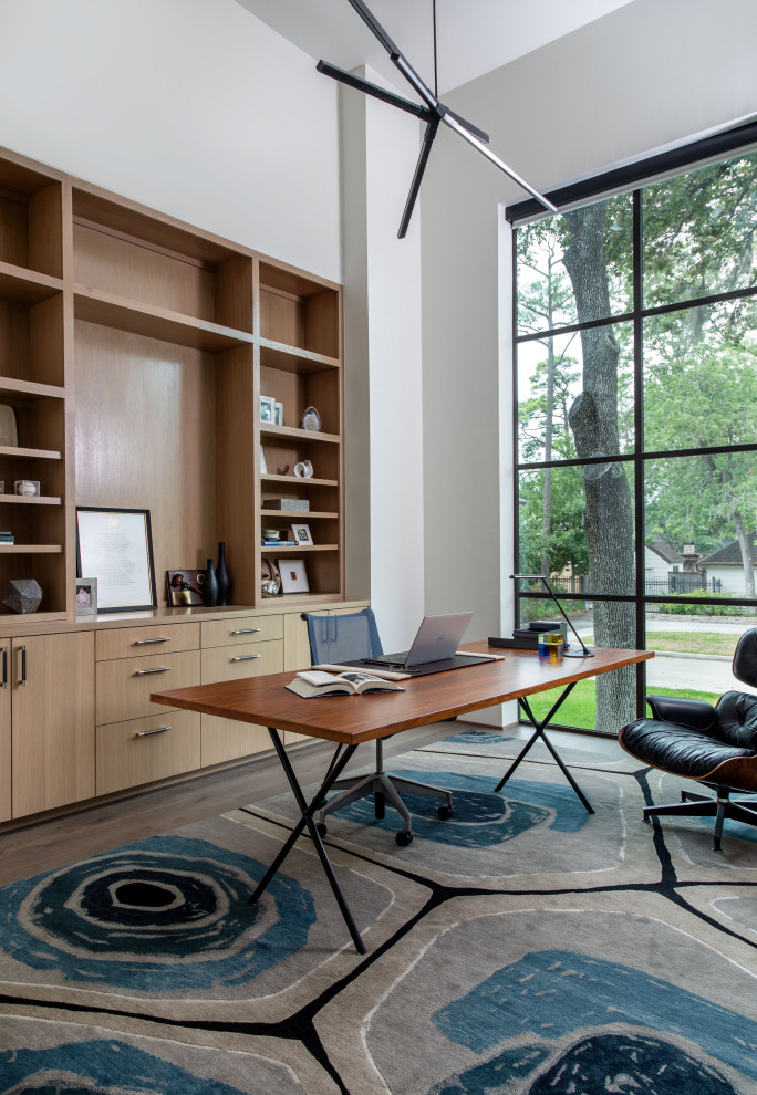 Example of a huge trendy freestanding desk medium tone wood floor and brown floor study room design in Houston with white walls