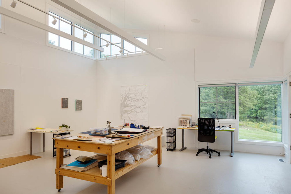 На фото: большая домашняя мастерская в стиле кантри с белыми стенами, бетонным полом и встроенным рабочим столом с