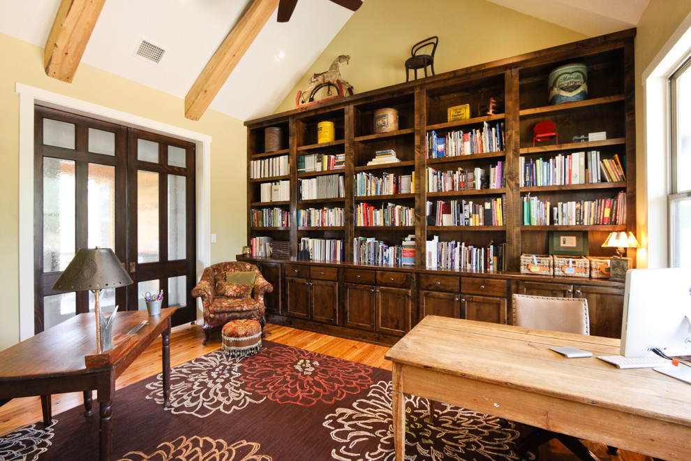 オースティンにある広いカントリー風のおしゃれなホームオフィス・書斎 (ライブラリー、ベージュの壁、無垢フローリング、暖炉なし、自立型机) の写真