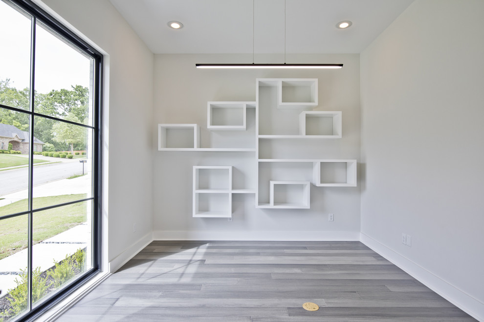 Großes Modernes Arbeitszimmer ohne Kamin mit Arbeitsplatz, weißer Wandfarbe, braunem Holzboden und grauem Boden in Sonstige