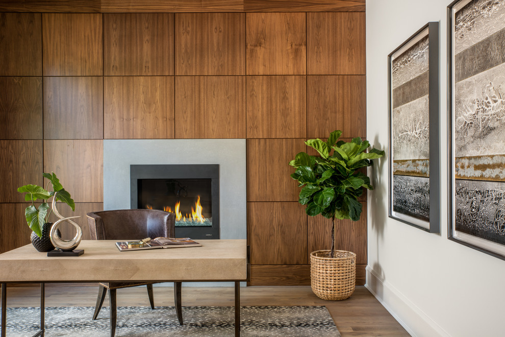 Cette photo montre un bureau chic avec un mur blanc, un sol en bois brun, une cheminée standard, un manteau de cheminée en béton et un bureau indépendant.