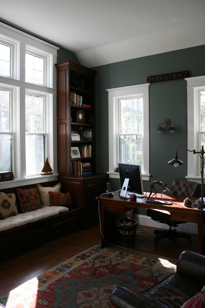 Exempel på ett litet klassiskt hemmabibliotek, med gröna väggar, mellanmörkt trägolv och ett fristående skrivbord