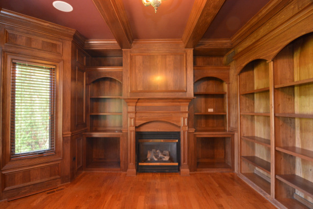 Foto de despacho tradicional con biblioteca, suelo de madera clara, marco de chimenea de madera, todas las chimeneas, casetón y boiserie