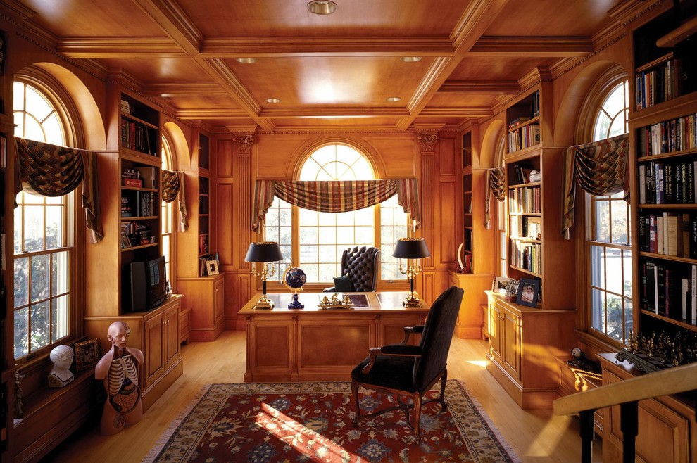 Klassisk inredning av ett arbetsrum, med mellanmörkt trägolv och ett fristående skrivbord