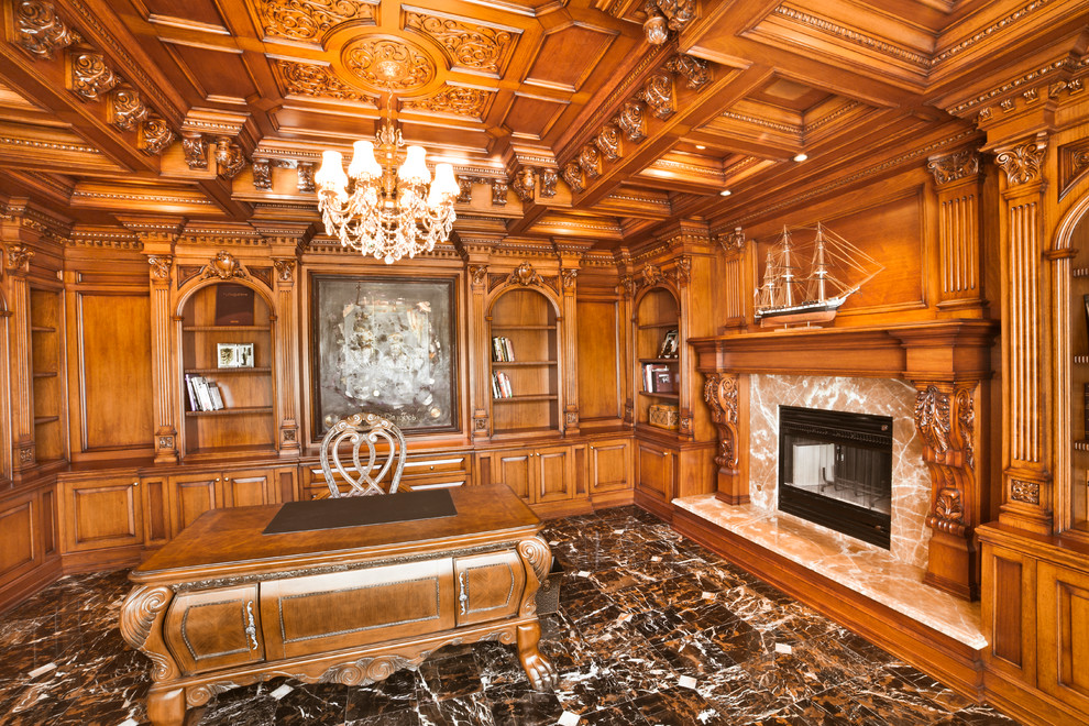 ニューヨークにある高級な中くらいなトラディショナルスタイルのおしゃれな書斎 (茶色い壁、大理石の床、標準型暖炉、石材の暖炉まわり、自立型机) の写真