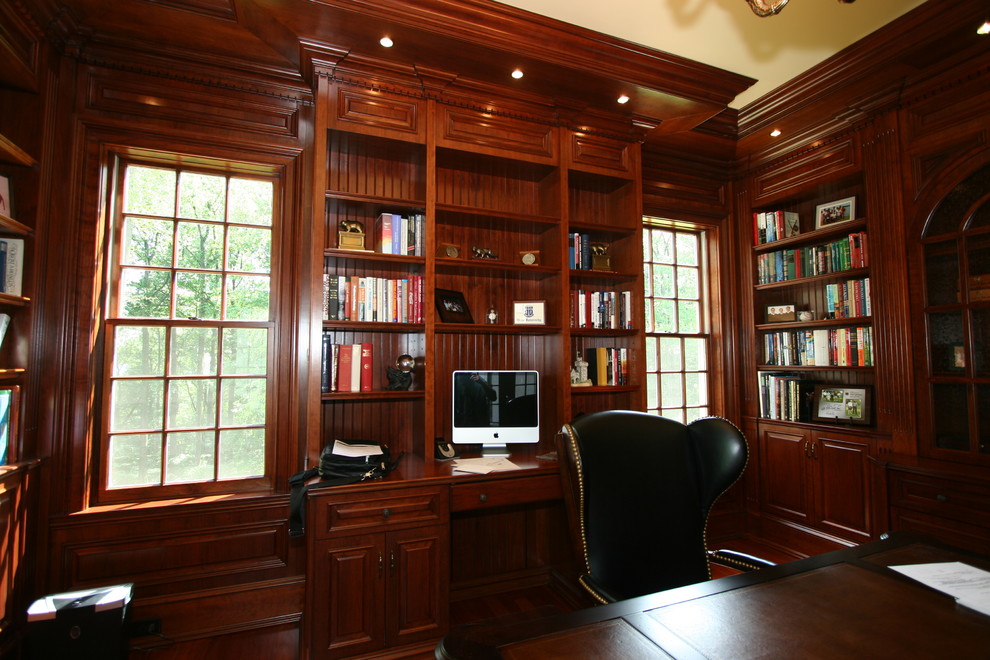 Klassisk inredning av ett mellanstort arbetsrum, med ett bibliotek, bruna väggar och ett inbyggt skrivbord