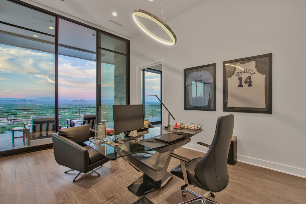 Imagen de despacho actual de tamaño medio sin chimenea con paredes blancas, suelo de madera en tonos medios, escritorio independiente y suelo marrón