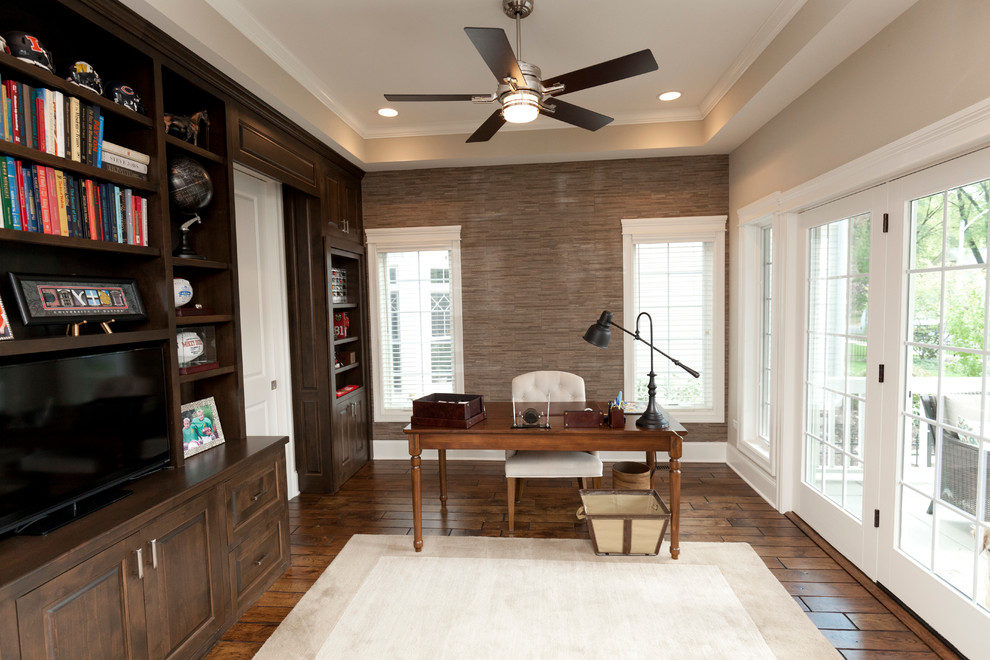 Modelo de despacho campestre de tamaño medio sin chimenea con paredes beige, suelo de madera en tonos medios y escritorio independiente