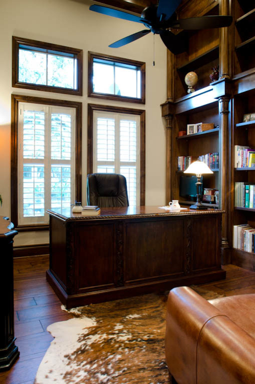 Geräumiges Klassisches Arbeitszimmer mit Arbeitsplatz, weißer Wandfarbe, hellem Holzboden und freistehendem Schreibtisch in Austin