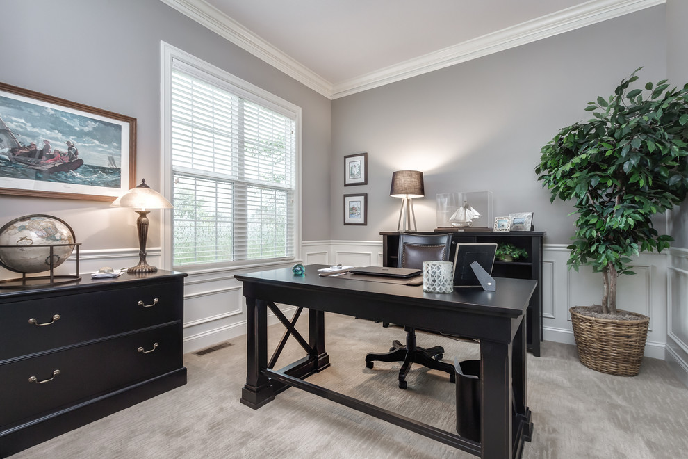 На фото: кабинет в стиле неоклассика (современная классика) с серыми стенами, ковровым покрытием, отдельно стоящим рабочим столом и серым полом без камина с