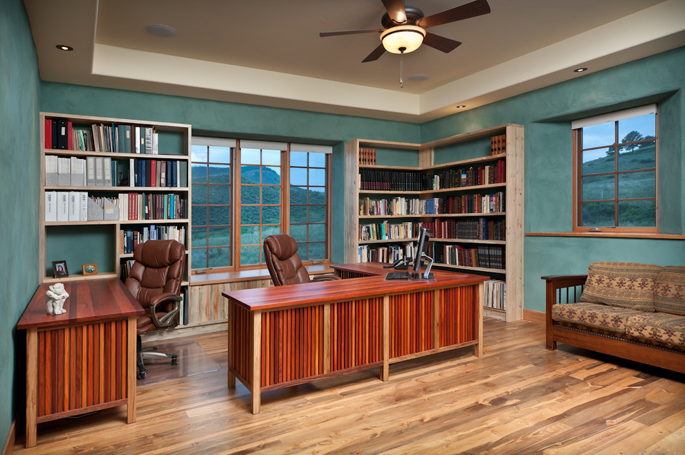 Großes Mediterranes Arbeitszimmer mit blauer Wandfarbe, braunem Holzboden und freistehendem Schreibtisch in Denver