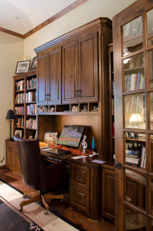 Inredning av ett klassiskt mellanstort hemmabibliotek, med beige väggar, mörkt trägolv och ett inbyggt skrivbord