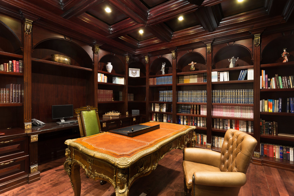 Exempel på ett mellanstort klassiskt hemmabibliotek, med mörkt trägolv, ett fristående skrivbord och bruna väggar