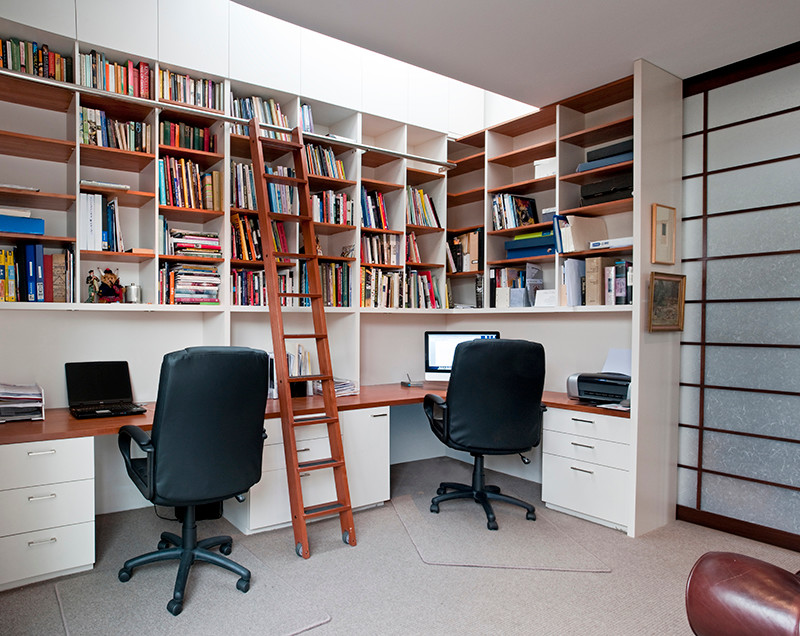 This is an example of a large contemporary home office in Melbourne with carpet, a built-in desk and white walls.