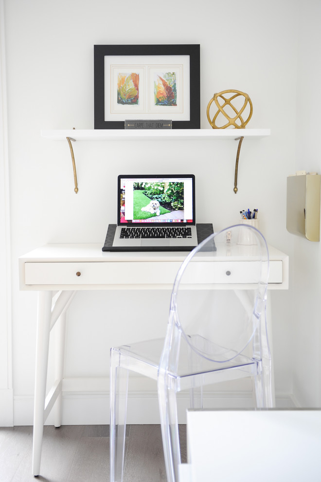 Immagine di uno studio minimalista di medie dimensioni con pareti bianche, pavimento in legno massello medio, nessun camino e scrivania autoportante