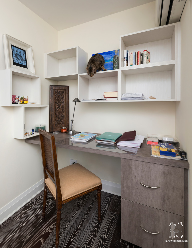 Foto på ett mellanstort funkis hemmabibliotek, med beige väggar, mellanmörkt trägolv och ett inbyggt skrivbord
