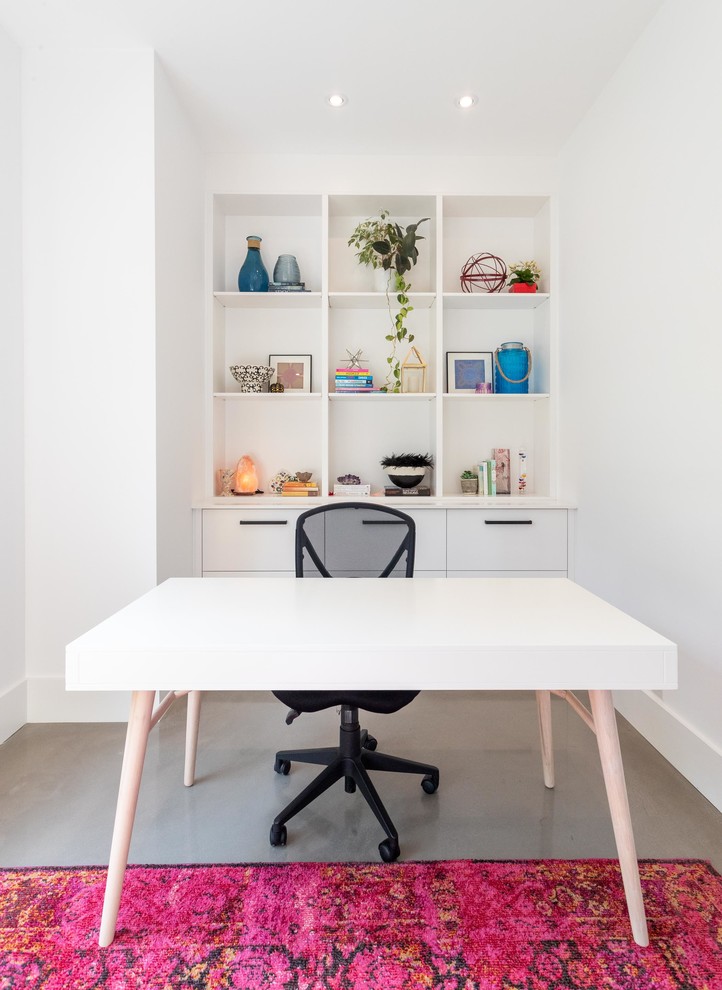 Diseño de despacho actual con paredes blancas, suelo de cemento, escritorio independiente y suelo gris