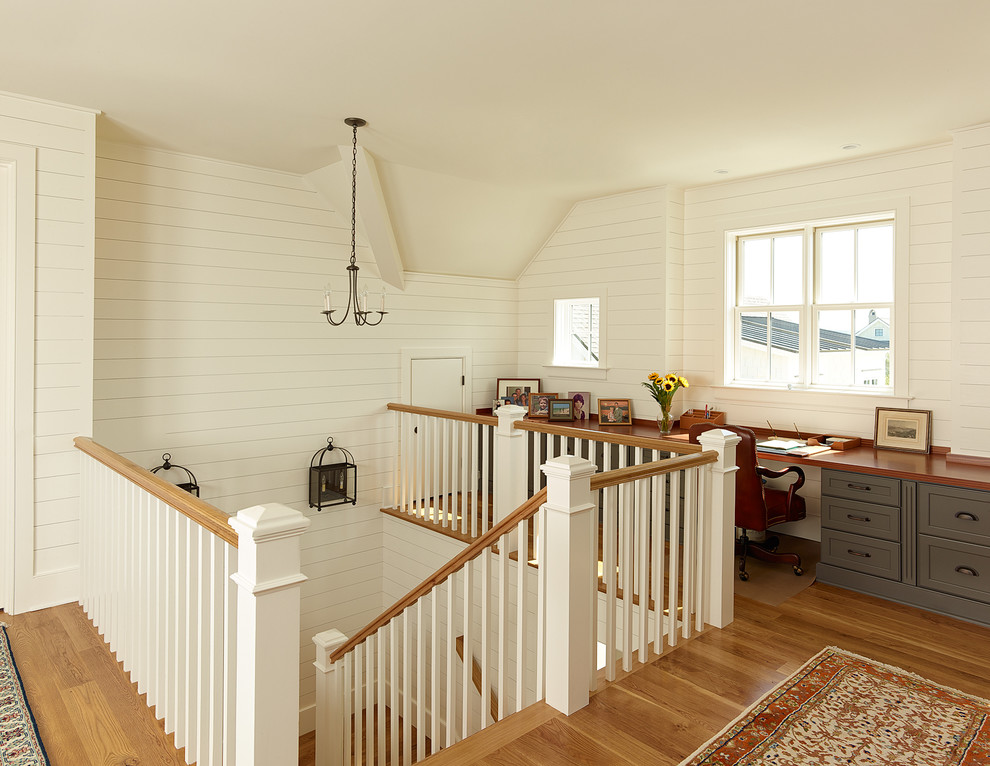 Idee per un piccolo studio stile marino con pareti bianche, pavimento in legno massello medio, scrivania incassata e pavimento marrone