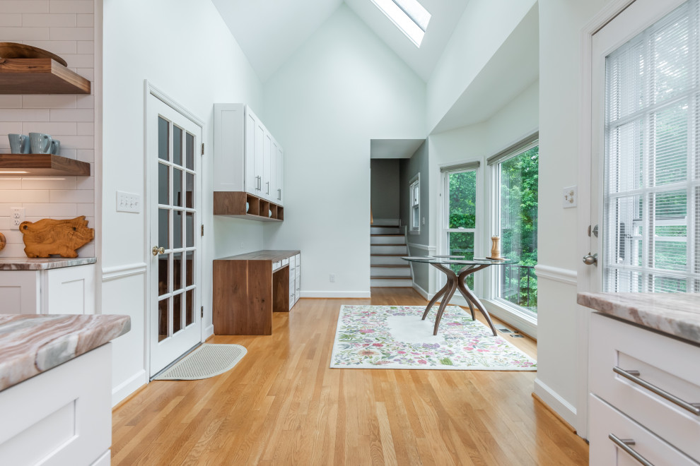 Imagen de estudio abovedado clásico renovado pequeño con paredes blancas, suelo de madera clara, escritorio empotrado y suelo marrón