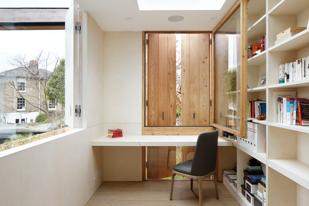 Foto de despacho actual sin chimenea con paredes blancas, suelo de madera clara, escritorio empotrado y suelo marrón
